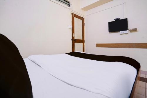 a bedroom with a white bed and a tv on the wall at Super Collection O Hubli City Center Formerly Chalukya Residency in Hubli