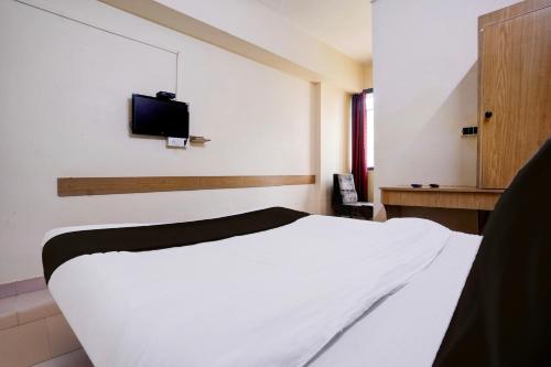 a bedroom with a white bed and a tv on the wall at Super Collection O Hubli City Center Formerly Chalukya Residency in Hubli