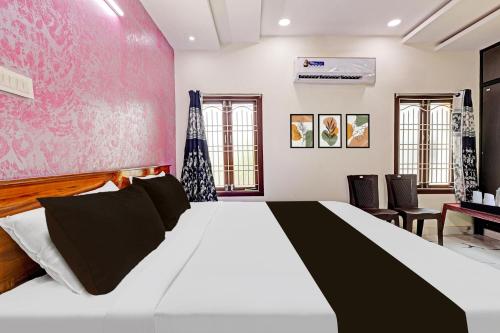 a bedroom with a large bed with a red wall at Super Hotel O Lakshmipuram Main Road Guntur in Guntūr