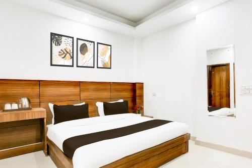 a bedroom with a large bed and a wooden headboard at Hotel O Cyber City Phase 3 in Gurgaon