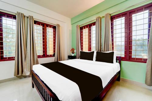 a bedroom with a large bed in front of windows at Super Collection O Kottayam Formerly Sap Inn in Kottayam
