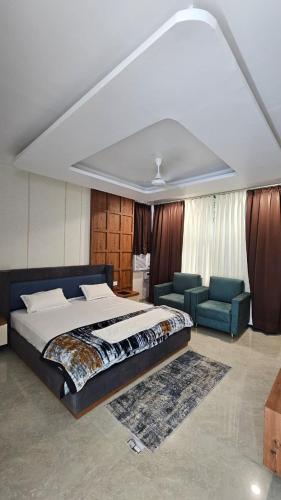 a bedroom with a bed and two blue chairs at Sri Rawatpura sarkar seva ashram in Haridwār