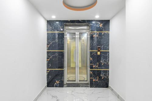 a bathroom with a glass door in a black tile wall at Super Collection O Mourigram Near Andul Road in Sānkrāil
