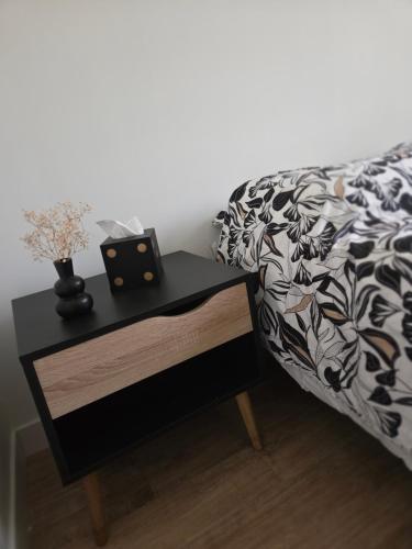 a black nightstand with a black and white bed at Chambre Cosy chez l'habitant - parking - spa -terrasse in Saint-Alban