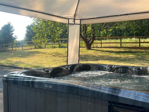 a hot tub filled with water next to a field at Hayy Luxury Retreat At The Lodge in Bradford