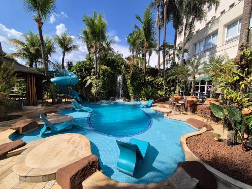 a large swimming pool with blue chairs and a waterfall at Beira Rio Palace Hotel in Piracicaba