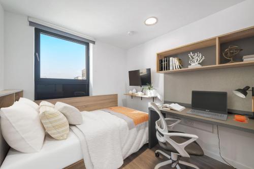 a bedroom with a bed and a desk with a computer at Student Only Canvas Walthamstow in London in London