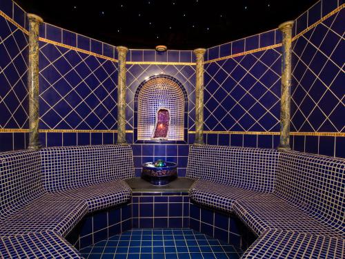 a blue tiled room with two benches and a mirror at Alpenhotel Tirolerhof in Neustift im Stubaital