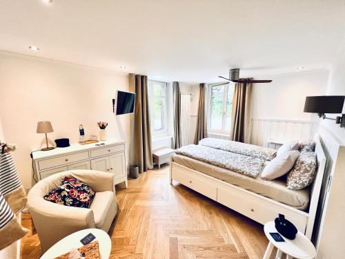 a bedroom with a bed and a chair at Boutique Hotel Niesenblick - direkt am Thunersee gelegen mit SELF CHECK IN & digitaler Rezeption in Oberhofen am Thunersee