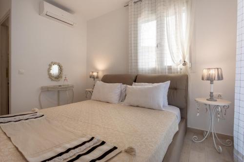 a white bedroom with a bed with white pillows and a window at Villa Thalassa in Skaleta