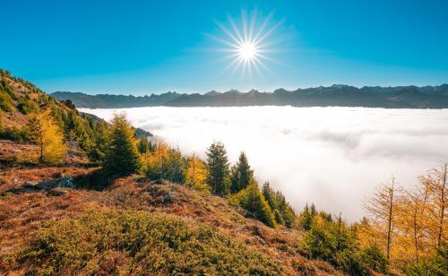 a view of a foggy valley with the sun above the clouds at Aparthotel Fernblick in Fiss