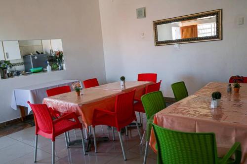 comedor con mesas, sillas y espejo en Onguti Guesthouse & Spa, en Windhoek