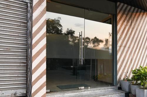 a glass door of a building with trees in it at Super Townhouse VIP Road Formerly The Sky in Kolkata