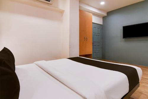 a bedroom with a white bed and a flat screen tv at Super Townhouse VIP Road Formerly The Sky in Kolkata