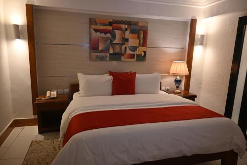 a hotel room with a large bed with a red blanket at GRAND Hôtel Akwa in Douala
