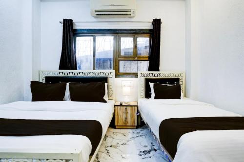 two beds in a room with a window at Super Hotel O Khar East Near Railway Station in Mumbai