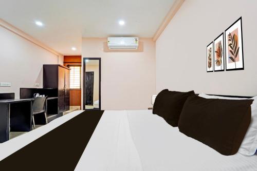 a bedroom with a large white bed with black pillows at Super Collection O Surathkal Beach in Suratakal