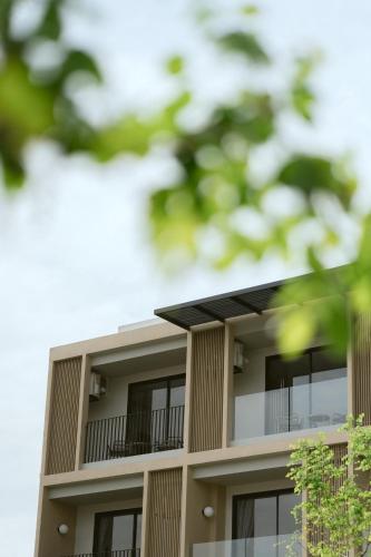 an apartment building with a balcony and trees at PAAK Hotel Suvarnabhumi in Lat Krabang