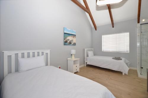 a white bedroom with a bed and a window at Ocean Breeze in Yzerfontein