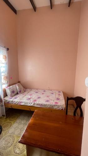 a small bedroom with a bed and a wooden table at Caribbean Charm in Calliaqua