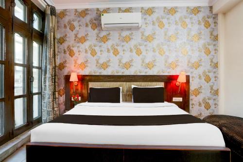 a bedroom with a large white bed in front of a wall at Super Hotel O Subhani Building Formerly Hotel Amandeep in Ludhiana