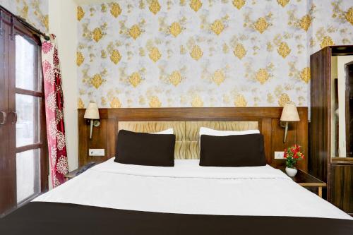 a bedroom with a white bed and a floral wallpaper at Super Hotel O Subhani Building Formerly Hotel Amandeep in Ludhiana