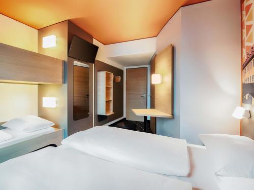 a bedroom with two beds and a mirror at B&B Hotel Bamberg in Bamberg
