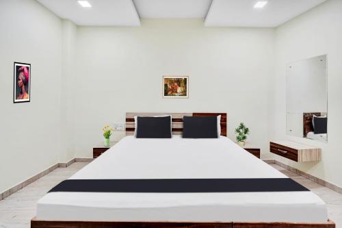 a bedroom with a large bed in a white room at Super Hotel O Chittorgarh City Center in Chittaurgarh
