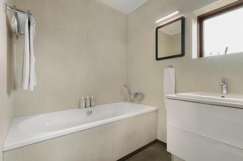 a white bathroom with a tub and a sink at Hotel Kriunes in Reykjavík