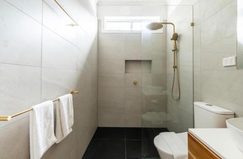 a bathroom with a shower and a toilet and a sink at The Lookout - Hamptons Treehouse in Narrabeen