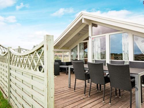 a wooden deck with a table and chairs on it at 6 person holiday home in Rømø in Bolilmark