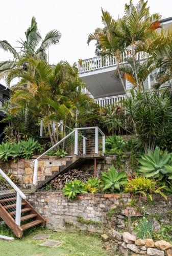 a staircase leading to a house with palm trees at The Lookout - Hamptons Treehouse in Narrabeen