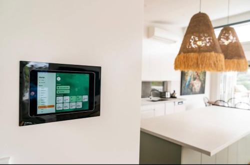 a kitchen with a small tv on the wall at The Lookout - Hamptons Treehouse in Narrabeen