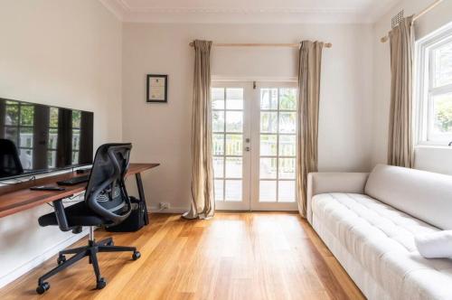a living room with a white couch and a desk at The Lookout - Hamptons Treehouse in Narrabeen
