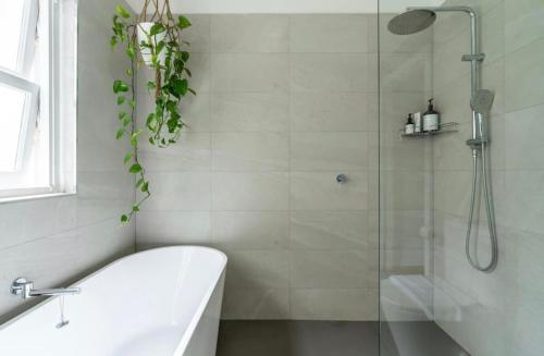 a bathroom with a shower with a tub and a sink at The Lookout - Hamptons Treehouse in Narrabeen