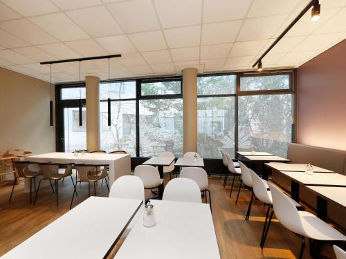 a dining room with tables and chairs and windows at B&B Hotel Berlin City-West in Berlin