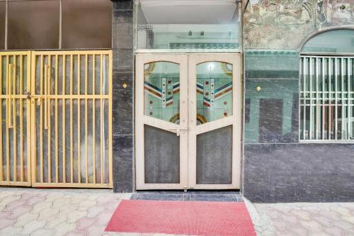 a pair of wooden doors on a building with a red rug at Super Hotel O Mall Road Gwalior formerly Rama inn in Gwalior