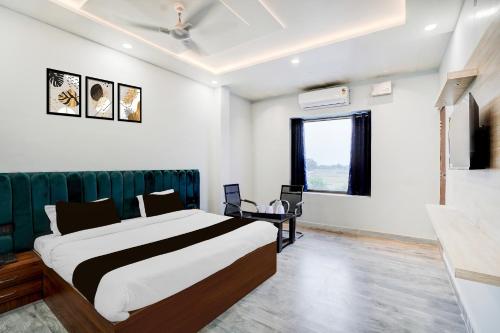 a bedroom with a large bed and a desk at Super Hotel O Hanuman Gadi Formerly Alankar Lawn in Varanasi