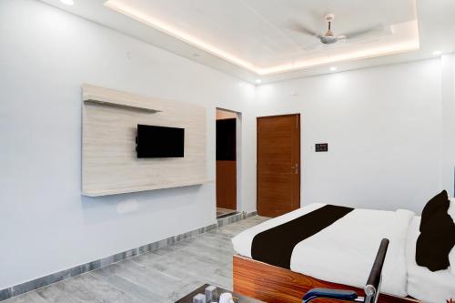 a bedroom with a bed and a tv on a wall at Super Hotel O Hanuman Gadi Formerly Alankar Lawn in Varanasi
