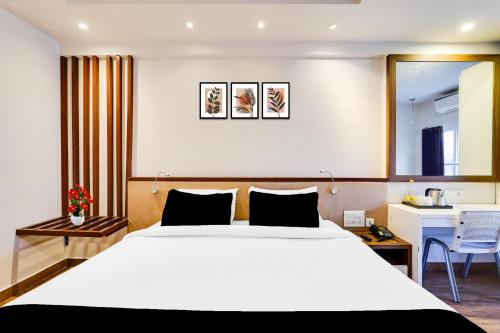 a bedroom with a large white bed and a desk at Super Townhouse Oak Kodambakkam Formerly Cine City in Chennai