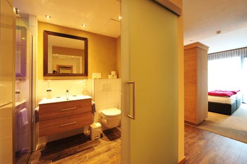 a bathroom with a toilet and a sink and a mirror at Aparthotel Fernblick in Fiss