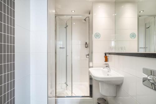 a white bathroom with a shower and a sink at Point A London Liverpool Street in London