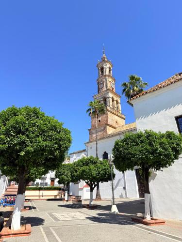 a building with a clock tower with trees in front of it at Apartamentos Bodeguetas in Constantina