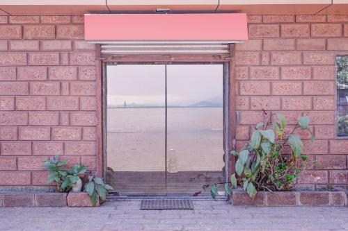 a brick wall with an open door to the beach at Super Townhouse Mahabaleshwar Formerly Shiva's Valley in Mahabaleshwar
