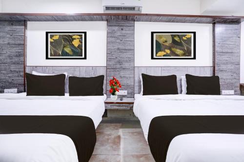 two beds in a room with two paintings on the wall at Super Townhouse Mahabaleshwar Formerly Shiva's Valley in Mahabaleshwar