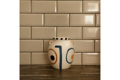 a white vase sitting in front of a brick wall at Waves Of Eros in Paralía