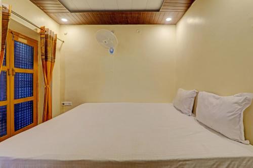 een slaapkamer met een wit bed en een ventilator bij Hotel O Home Shyama Lodge in Ayodhya