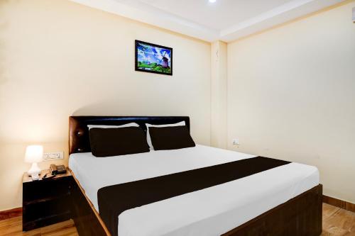 a bedroom with a white bed with a black and white sheets at Super Collection O Last Gate Near Dispur Law College Formerly RR hotels in Dispur