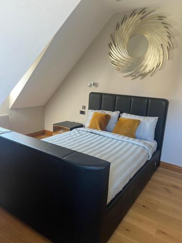 a bedroom with a bed with a black headboard and a mirror at Turnhams Gill located near high street in Henfield