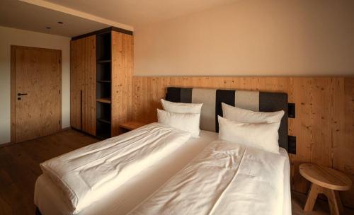 a bedroom with a large bed with white sheets and pillows at ADEA Lifestyle Suites Fieberbrunn in Fieberbrunn